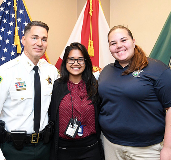 Student poses for a photo with her supervisor and the sheriff.