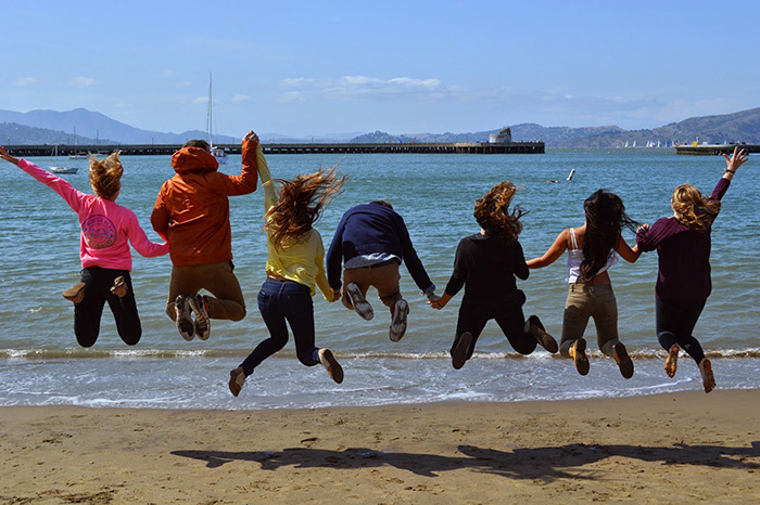 Students jumping at a beach