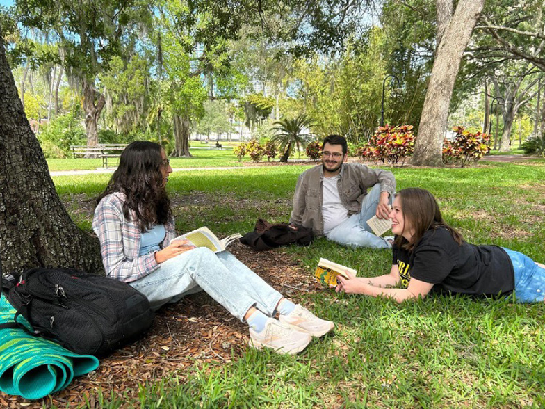 Students reading and talking under a tree.
