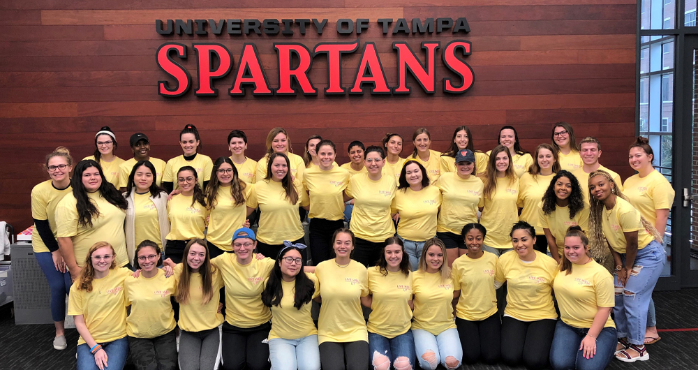 Students standing in front of a University of Tampa Spartans sign 