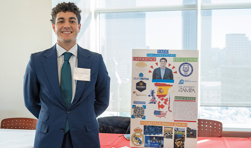 YAGO FERNANDEZ-FIGARES STANDING IN FRONT OF A POSTER