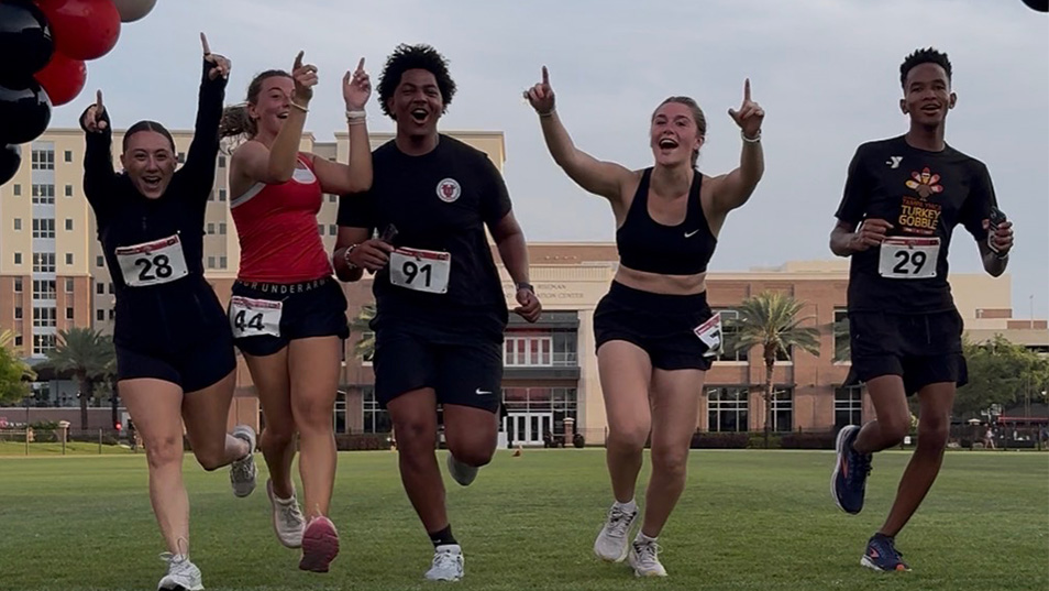 A group of runners wearing race numbers pinned to their shirts